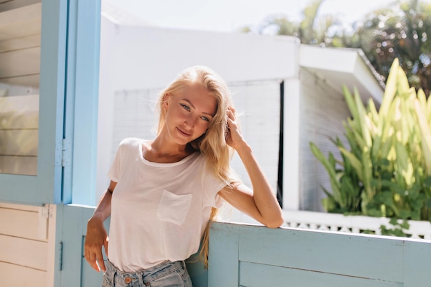 Dreamy girl with light long hair standing near window Attractive white woman posing on nature background with romantic face expression