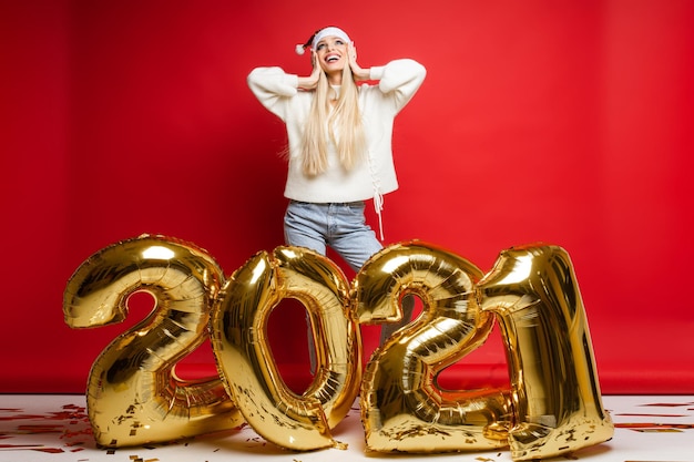 Dreamy happy caucasian girl in santa hat looking up make wish. Smiling female dream visualize happiness in 2021 New Year