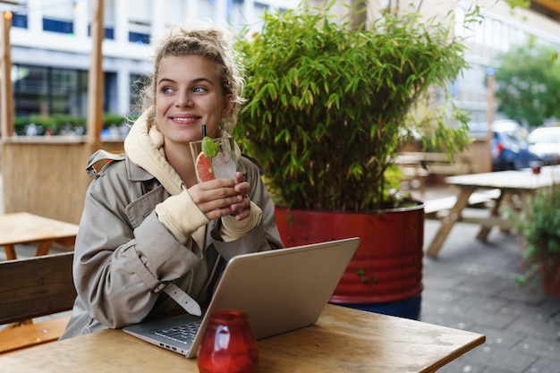 Dreamy happy girl enjoying a drink in a cafe while having break work.
