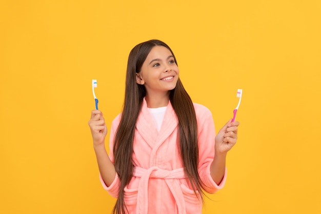 Dreamy happy teen girl in home terry bathrobe hold toothbrush health