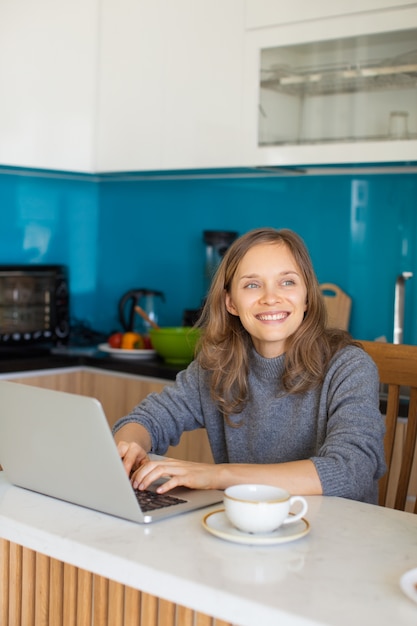 Dreamy Lady Working on Laptop in Kitchen