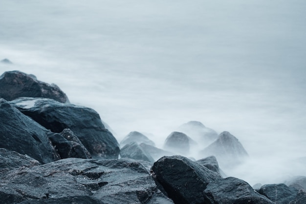 Dreamy natural background with sea shore, rocks and waves. Long exposure. Black and white