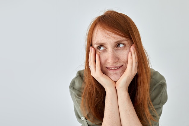 Dreamy redhead woman touching face and smiling gently