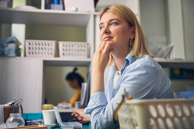 Photo dreamy specialist looking away while touching a chin with hand