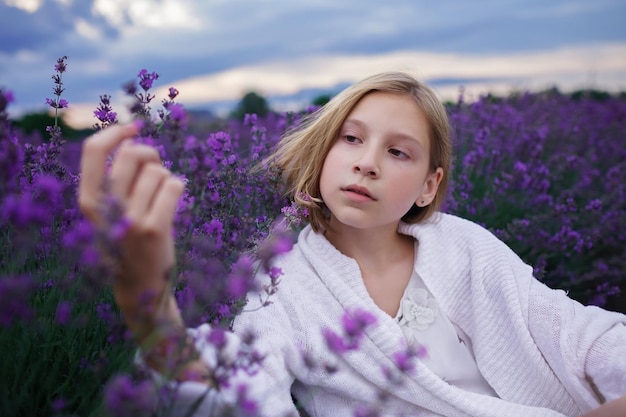 La ragazza sognante dell'adolescente cammina tra i fiori viola durante le bellissime vacanze estive al tramonto