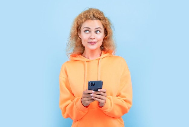 Dreamy woman chat on smartphone isolated on blue background woman chat on smartphone