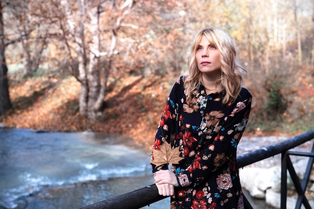 Dreamy woman in dress on bridge in autumn forest