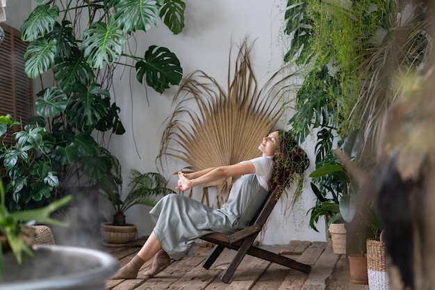 dreamy woman relaxing in tropical resort-style garden at home female gardener resting in greenhouse