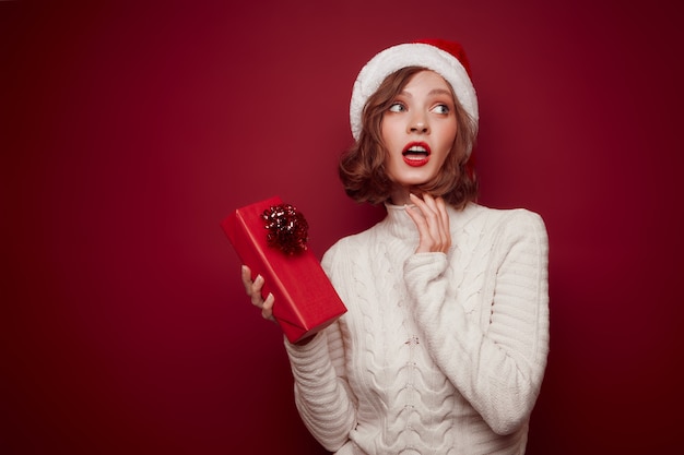 Foto donna sognante con cappello da babbo natale con regalo