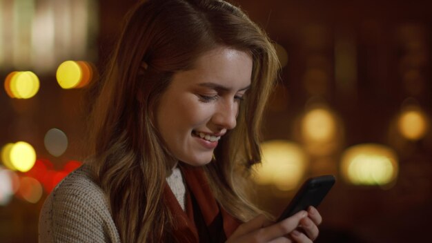 Dreamy woman sending message phone on street Smiling girl relaxing with phone