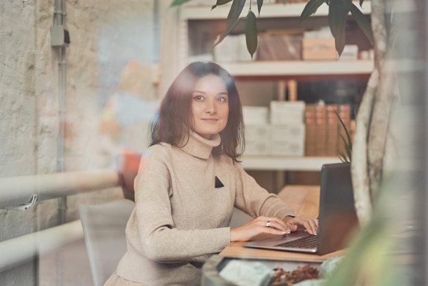 Dreamy woman using laptop in office