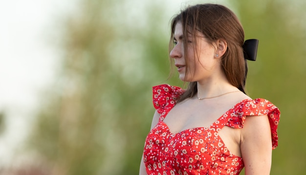 Dreamy young attractive woman in a red dress and a black ribbon in her hair