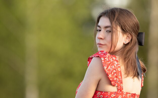 Dreamy young attractive woman in a red dress and a black ribbon in her hair