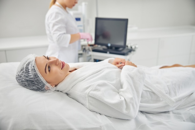 Dreamy young lady lying on the couch before a cosmetic procedure in a dermatologist office