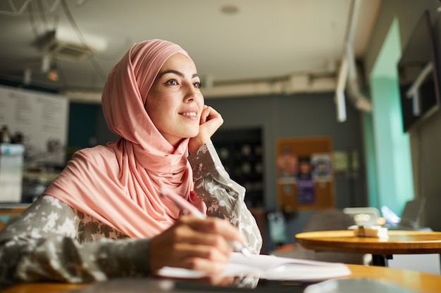 Dreamy young woman writing in diary