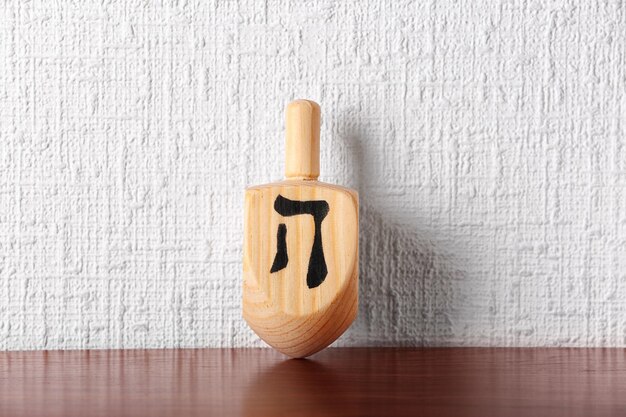 Foto dreidel per hanukkah su un tavolo di legno contro una parete di texture chiare