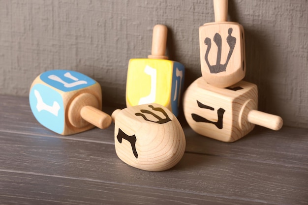 Dreidels for Hanukkah on wooden table against grey textured wall