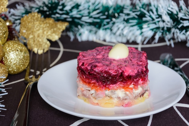 Dressed herring or herring under a fur coat. Symbol of the new year. Traditional Russian cuisine. Christmas decorations in the background. New Year's concept.