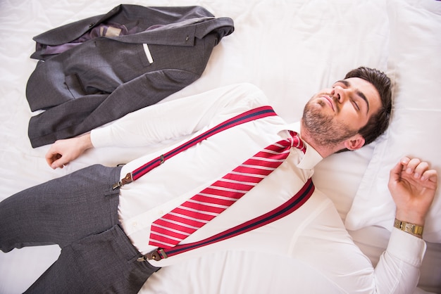 Dressed man lay on bed after hard road.