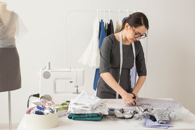 Dressmaker, fashion designer and tailor concept - beautiful young stylist at workplace near rack with clothes.