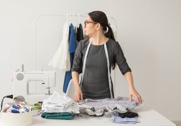 Dressmaker, fashion designer and tailor concept - beautiful young stylist at workplace near rack with clothes.