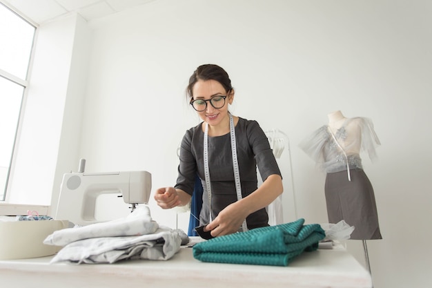 Dressmaker, fashion designer, tailor and people concept - Portrait of a seamstress at work in her own studio.