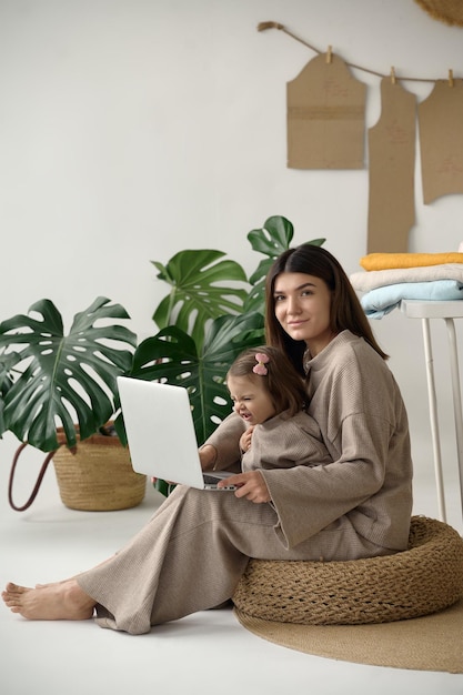 Портниха шьет одежду в своей студии со своей дочерью