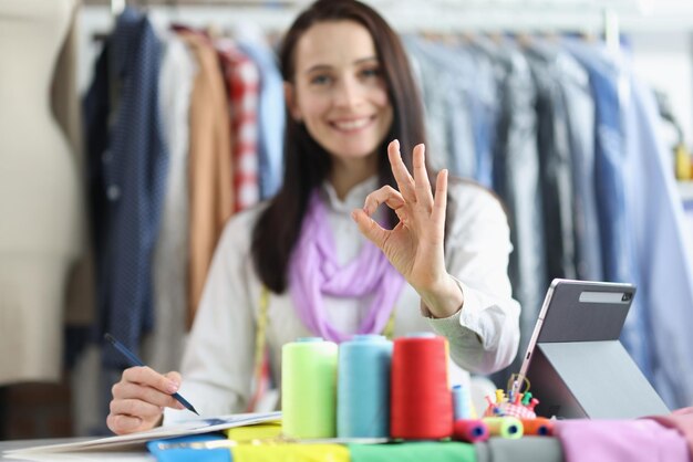 Dressmaker woman holding ok gesture while working in studio