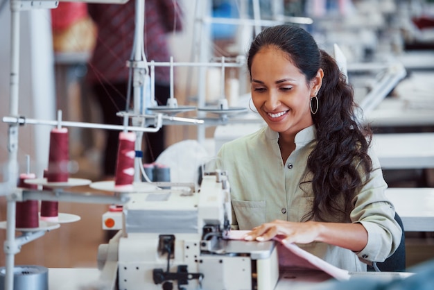 Dressmaker woman sews clothes on sewing machine in factory.