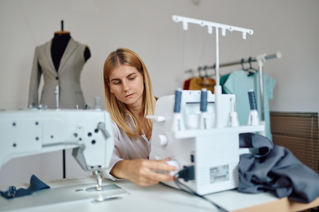 Dressmaker works on sewing machine at workplace