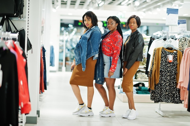 Drie aantrekkelijke Afro-Amerikaanse vrouw in bruine tuniekjurk poseerde bij kledingwinkel Het is tijd om te winkelen