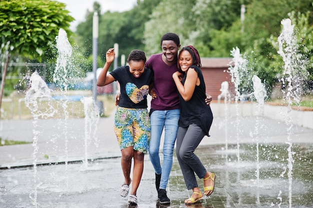 Drie Afro-Amerikaanse vrienden die op fonteinen lopen Samen plezier maken