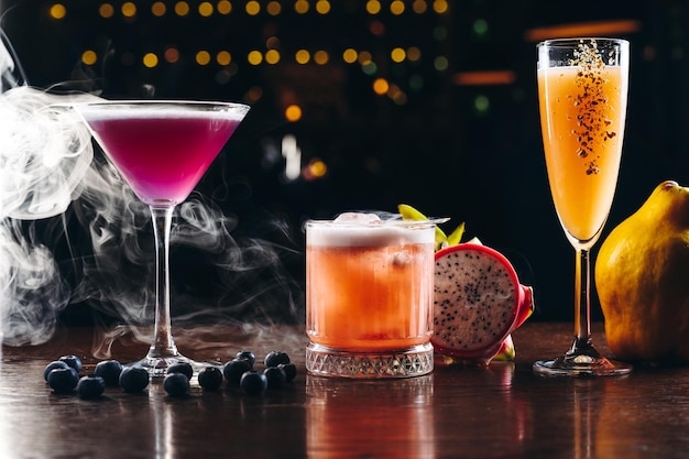 Drie alcoholische cocktails paars-oranje en gele kleuren op tafel Verscheidenheid aan kleurrijke alcohol