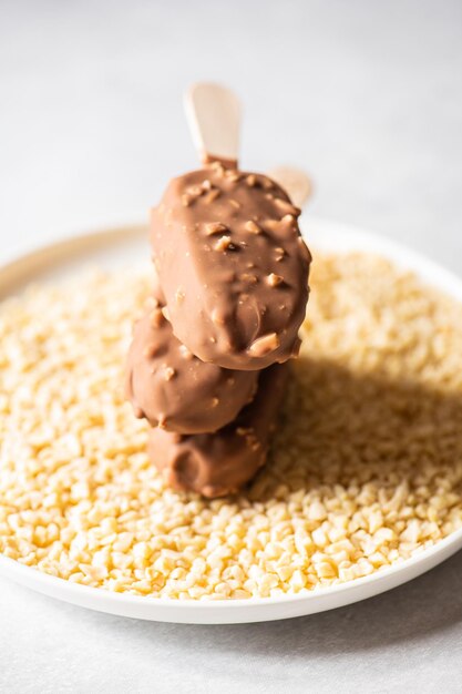 Drie amandel-vanille-ijs op een stokje met chocoladeglazuur