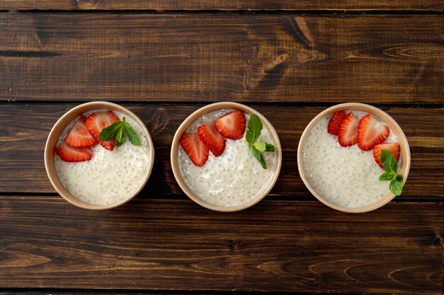 Drie ambachtelijke papieren bekers met tapiocapudding met plantaardige melk. bovenaanzicht