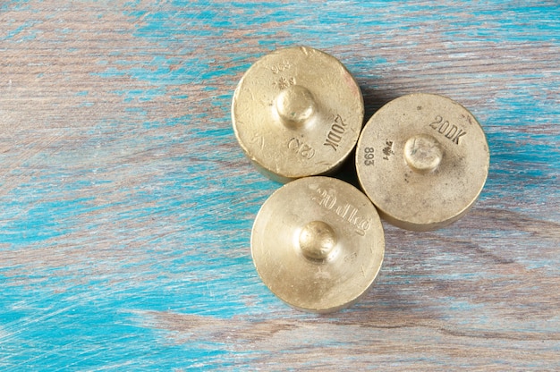 Drie antieke bronzen gewichten voor schalen op blauwe houten achtergrond. kopieer ruimte voor rekwisieten voor tekst en voedselfotografie.