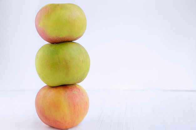 Drie appels gestapeld tegen een witte achtergrond met een kopie ruimte