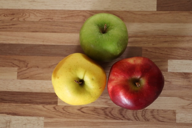 Drie appels op een houten tafel rode appel gele appel en groene appel