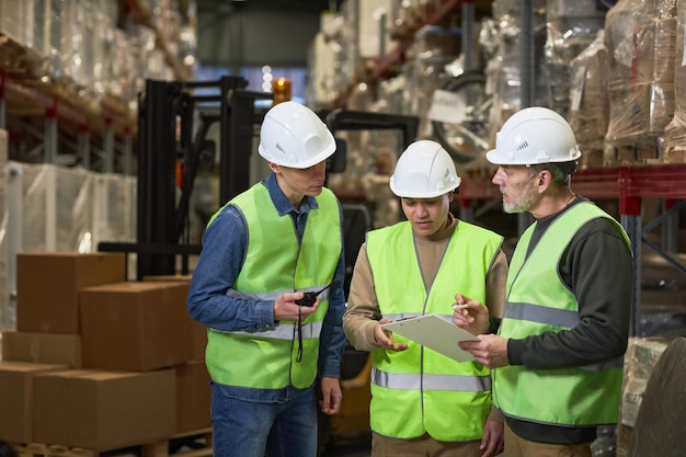 Drie arbeiders die inspectie in het klembord van de pakhuisholding doen