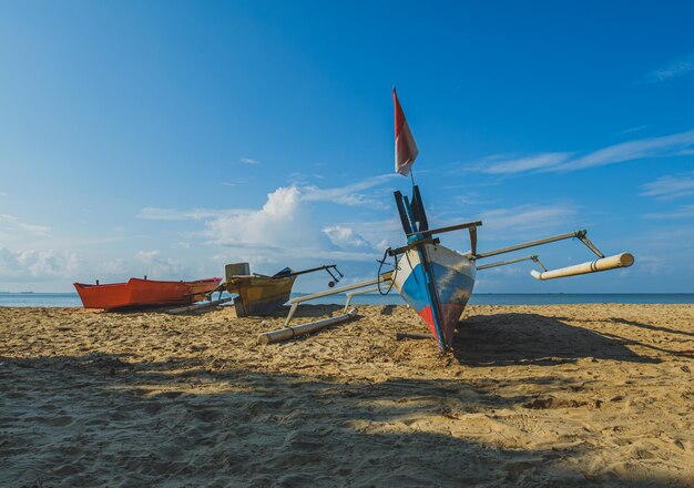 Foto drie boten rusten op een zandstrand één boot met een indonesische vlag