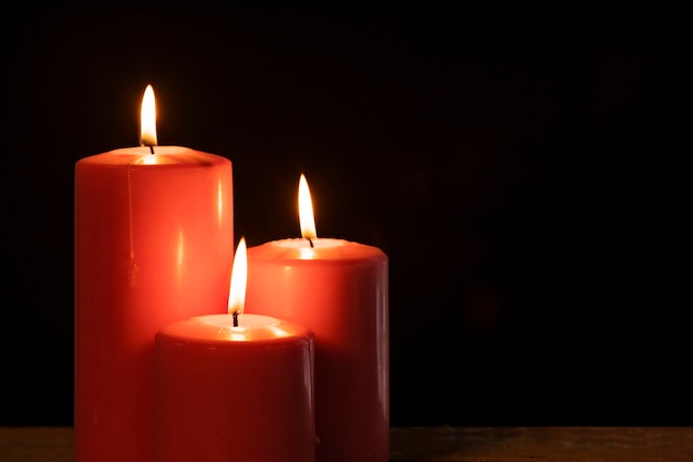 Drie brandende kaarsen met donkere achtergrond
