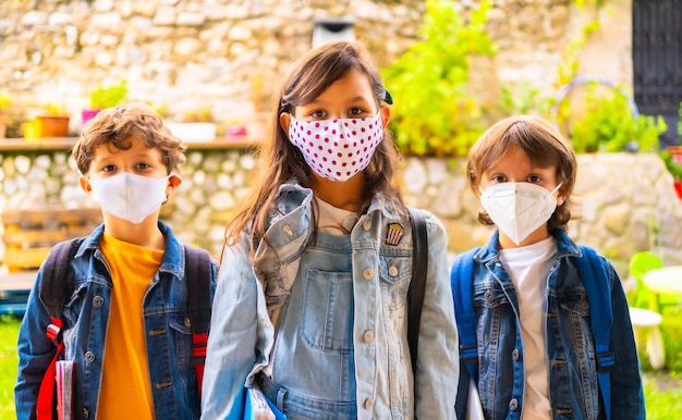 Drie broers kinderen met gezichtsmaskers klaar om terug te gaan naar school. nieuwe normaliteit, sociale afstand, coronavirus-pandemie, covid-19.