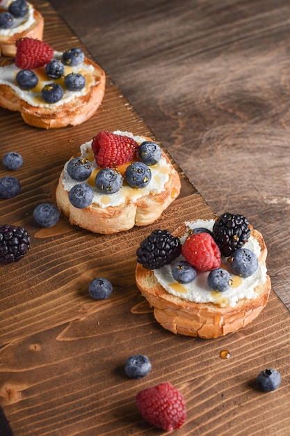 Drie bruschetta met roomkaas en bessen op de houten tafel Horizontaal bovenaanzicht Kopieer de ruimte