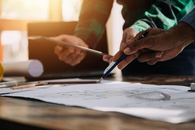 Drie collega's bespreken data werken en tablet laptop met op architectonisch project op bouwplaats aan bureau in kantoor