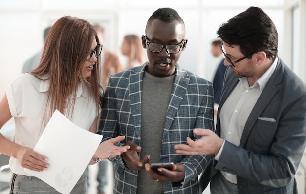 Drie collega's die naar het scherm van de smartphone kijkenmensen en technologie