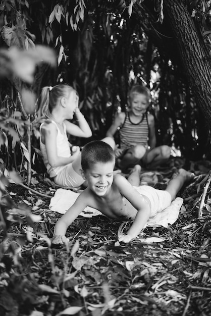 Drie dorpskinderen spelen in een hut die ze zelf hebben gebouwd van bladeren en takjes houten huis in het bos zwart-wit fotografie