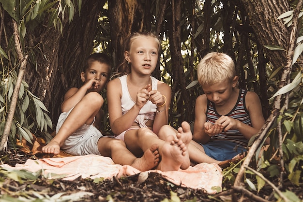 Drie dorpskinderen spelen in een hut die ze zelf hebben gebouwd van bladeren en twijgen