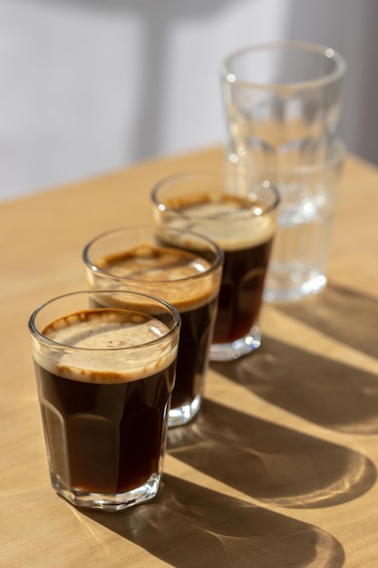 Drie espressokoffie in glazen kopjes op een houten tafel Kopieer de compositie van de ruimte met schaduwen