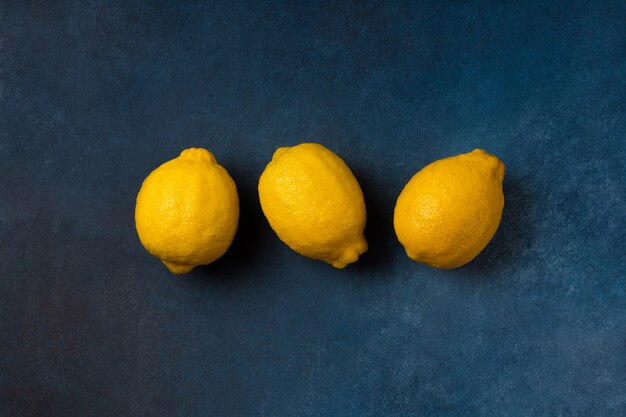 Drie felgele citrusvruchten op een blauwe achtergrond bovenaanzicht