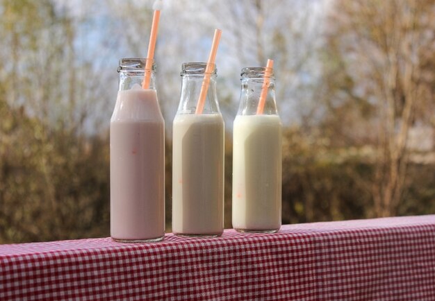 Drie flessen milkshake op houten tafel naast het uitzicht op de rivier